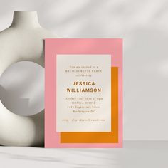 a pink and orange party card next to a vase