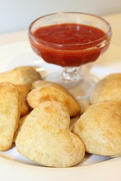 some heart shaped pastries on a plate with a small bowl of ketchup