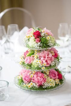 three tiered cake decorated with pink and white flowers on top of a round table