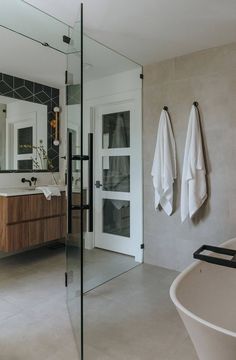 a bathroom with a tub, sink and mirror next to it's doors that are open