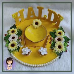 a yellow hat with daisies and pearls on the bottom is surrounded by other flowers