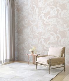 a chair sitting in front of a window next to a vase with flowers on it