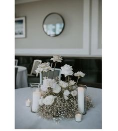 white flowers and candles are arranged on a table in front of a mirror at a wedding reception