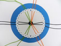 a white clock with orange and green wires connected to it on a blue circular surface