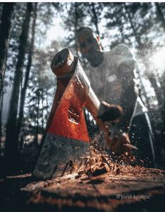 a man using a chainsaw to cut wood in the woods with trees behind him