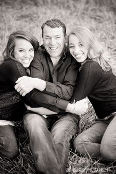 two women and a man are sitting on the ground together, posing for a black and white photo