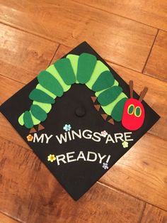 the very hungry caterpillar is on top of this black graduation cap that says, my wings are ready