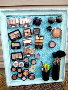 a display case filled with cosmetics and makeup brushes on top of a blue tablecloth