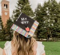 a woman wearing a graduation cap with the words my why written on it in front of a clock tower