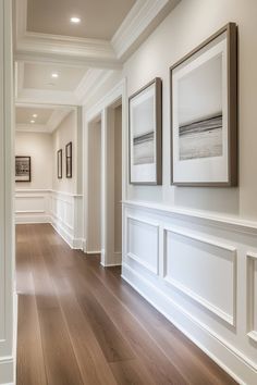 an empty hallway with two framed pictures on the wall and hard wood flooring in front of it