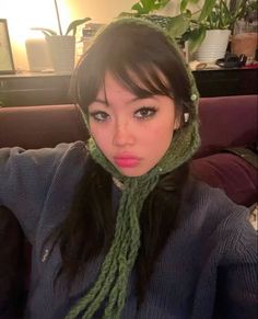 a young woman wearing a green scarf around her head and looking at the camera while sitting on a couch