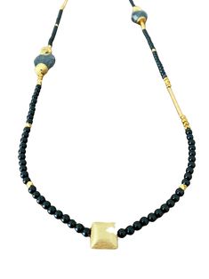 This asymmetrical necklace offers a unique and versatile design that can be worn long or double-wrapped for a shorter necklace style. The necklace showcases a combination of onyx gemstones, gold bars, and gold beads, creating an exquisite and eye-catching piece of jewelry. It measures approximately 40 inches in length, allowing for various styling options. The onyx gemstones are the focal point of the necklace, adding a rich and captivating deep black hue. Onyx is a semi-precious gemstone known Gold Onyx Gemstone Beaded Necklaces, Gold Onyx Beaded Necklaces With Gemstone Beads, Gold Onyx Necklaces With Natural Stones, Gold Necklaces With Black Beads Long Shape, Gold Long Necklace With Gemstone Beads, Asymmetrical Necklace, Gold Bars, Asymmetrical Design, Gold Bar