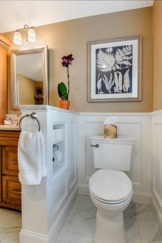 a white toilet sitting in a bathroom next to a wooden vanity and mirror above it