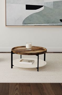 a coffee table with a cup on it in front of a painting and wooden flooring