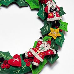 a christmas wreath made out of felt with santa claus and other holiday decorations on it