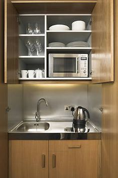 a small kitchen with wooden cabinets and stainless steel appliances, including a microwave above the sink