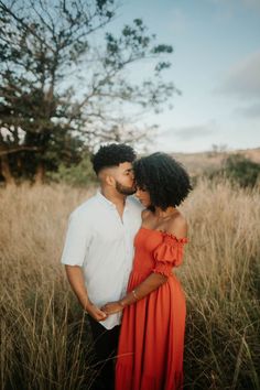 a man and woman are standing in tall grass with their heads close to each other