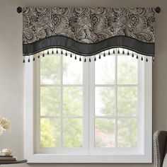 a living room with a chair and window in front of the window, it has an ornate valance