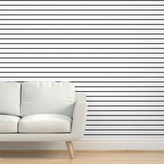 a white couch sitting in front of a blue and white wall with vertical lines on it