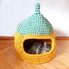 a cat laying in a crocheted bed on the floor next to a wall