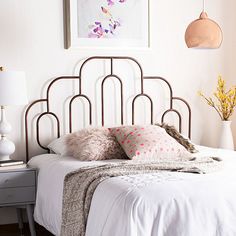 a bed with white sheets and pink pillows