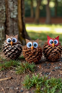 three pine cones with googly eyes are sitting on the ground in front of a tree