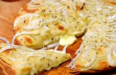 a close up of a pizza on a wooden cutting board with cheese and onion toppings