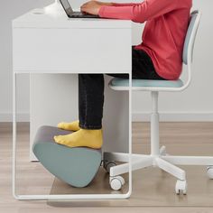 a person sitting at a desk with their feet up on a chair and using a laptop