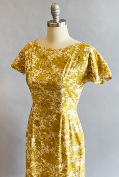 "1950s cotton sateen very fitted day dress. Ivory ground with an all over mustard brush stroke floral print. The neckline is pointed scallops. Top-stitched seams across the bodice, as well as form fitting vertical seams front and back. Cap sleeves, a V-back, with a metal zipper and hook and eye closure. Size- Small Bust - 34\" Waist - 27\" Hips - 39\" Length - 39\" Label: Janice Jr. Condition: Excellent vintage condition. All vintage is sold in \"as-is\" condition. We do our best to inspect, cor Yellow Fitted Dress In 1950s Style, Fitted Yellow Dress In 1950s Style, 1950s Style Yellow Dress For Garden Party, Yellow 1950s Style Dress For Garden Party, Mid-century Fitted Dress With Vintage Print, Fitted Vintage Mustard Dress, Mustard Fitted Floral Print Dress, Fitted Mustard Floral Print Dress, Mustard Fitted Cotton Dress