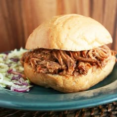 a pulled pork sandwich with coleslaw on a blue plate