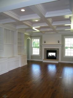 an empty living room with hard wood flooring and white painted walls on either side of the fireplace