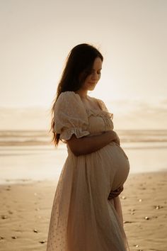 a pregnant woman standing on the beach at sunset with her belly wrapped around her waist