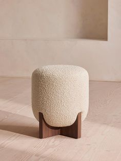 a sheep stool sitting on top of a hard wood floor next to a white wall