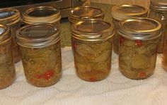 several jars filled with pickles sitting on top of a white table cloth next to an oven