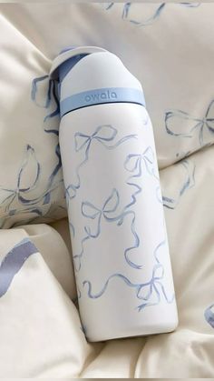 a white and blue water bottle sitting on top of a bed covered in sheets with butterflies