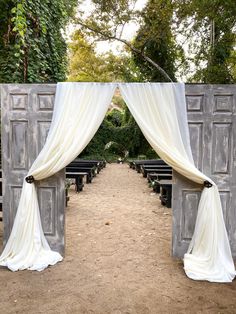 an outdoor ceremony with white drapes and black benches