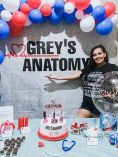 a woman standing in front of a cake and balloons