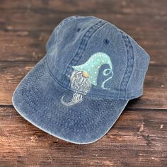 a blue hat with an owl on it sitting on top of a wooden table next to a