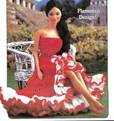 a crocheted doll sitting on a chair in a red dress with white ruffles