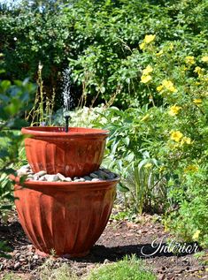 two large clay pots with water coming out of them in the middle of a garden