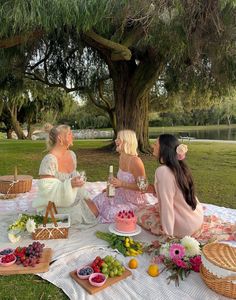 three women sitting at a picnic table with food and drinks