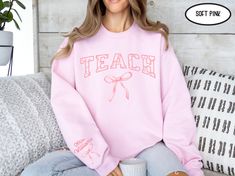 This adorable Coquette Teach shirt is the perfect addition to any teacher's wardrobe. This would make a great personalized gift for teacher appreciation, your favorite teacher's birthday gift, or a graduation gift for a new teacher.  ✅ Ships in 3-6 business days. ✅ Sweatshirt comes in 7 colors (Light Pink, Sand, White, Black, Military Green, Dark Heather, and Sport Gray). ✅ Printed on the Gildan 18000 sweatshirt. ✅ All shirts are unisex sizing. Please see sizing charts in pictures and see sizing Personalized Casual Tops For Teacher Appreciation, Teach Shirt, Teacher Graduation Gifts, Teacher Graduation, Teacher Birthday Gifts, Teacher Wardrobe, Graduating Teacher, Teacher Birthday, Teaching Shirts