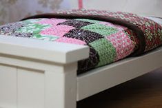 a white bed frame with a patchwork quilt on it's top and bottom