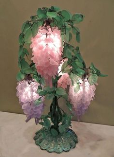 a vase filled with pink and purple flowers on top of a white tablecloth covered table