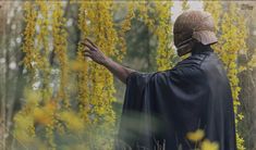 a man dressed as darth vader standing in the woods with his hand out