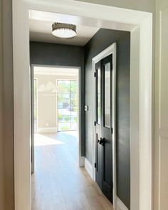 an empty hallway leading into a house with gray walls and white trim on the doors