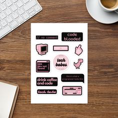 a sticker sheet with pink and black text on it next to a cup of coffee