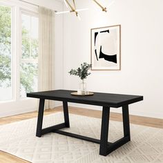 a black table sitting on top of a wooden floor next to a vase with flowers