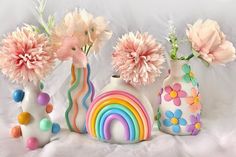 there are three vases with flowers in them and one has a rainbow on it