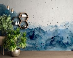 a room with blue watercolor paint on the wall and potted plants next to it